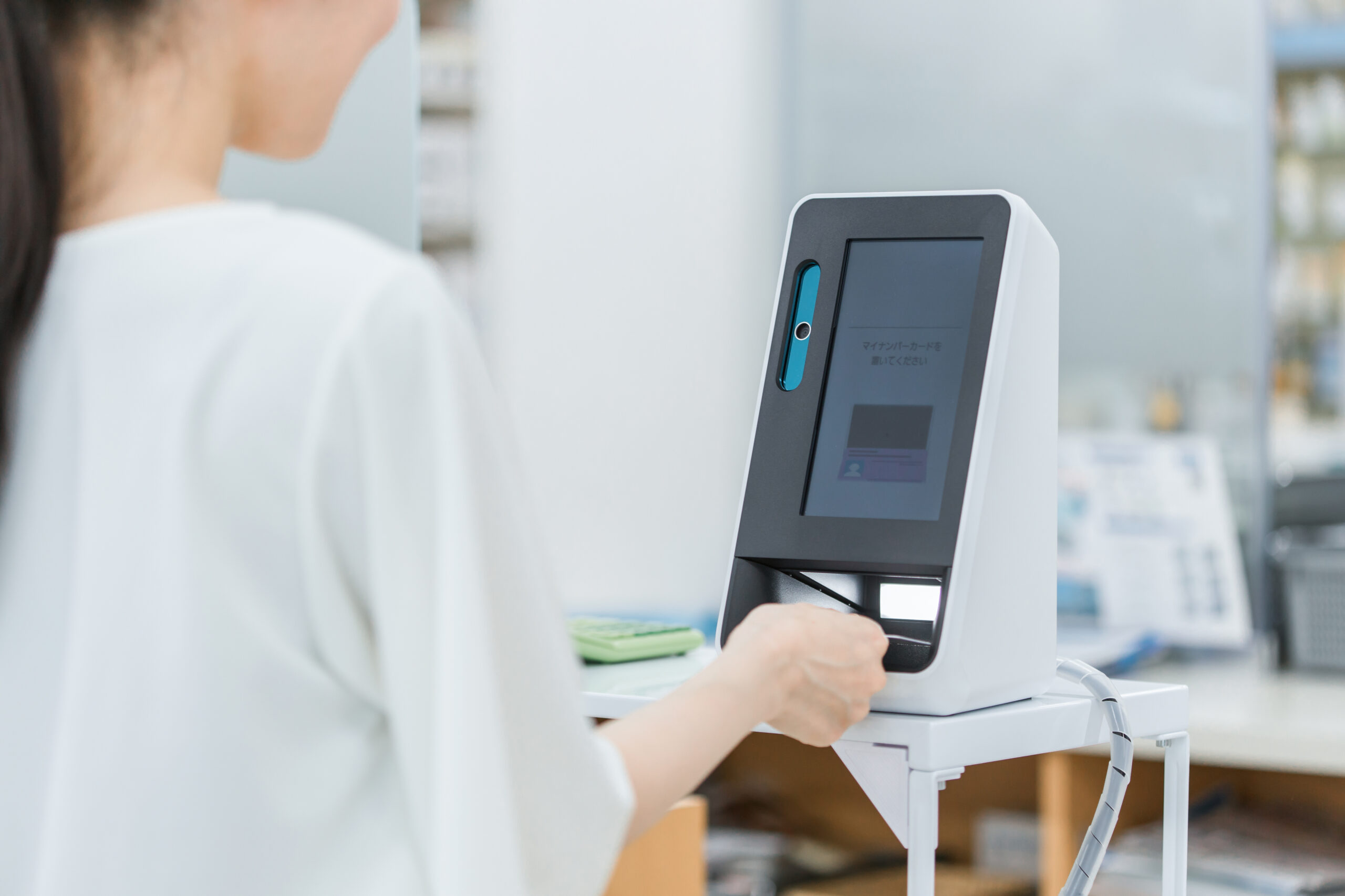 電子機械で薬局の受付をする女性